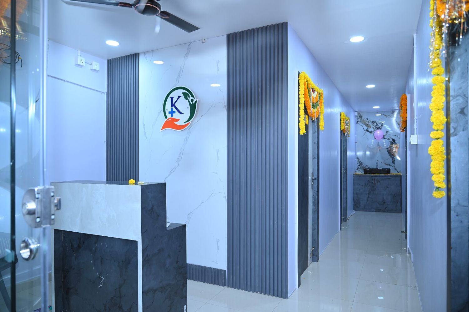 The reception corridor at Khushi Polyclinic, with a pale stone wall and grey panels.
