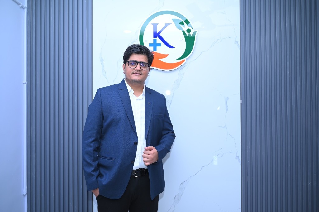Dr. Balaji Varvatte at Khushi Polyclinic, in a navy blazer and glasses, standing by the clinic mark.